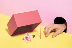 The hand from the hole wants to steal the rose flower from the trap. Pastel surreal concept.